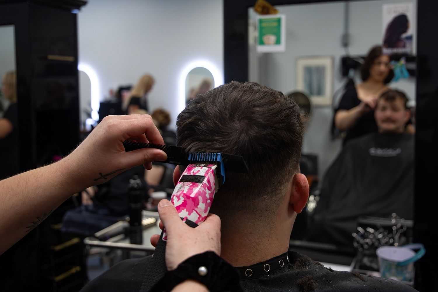 Man getting a haircut in a busy barbershop.