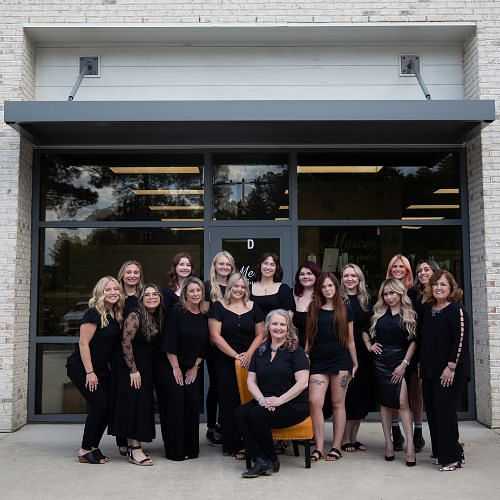 Group photo of women in black attire standing and seated outside a building.